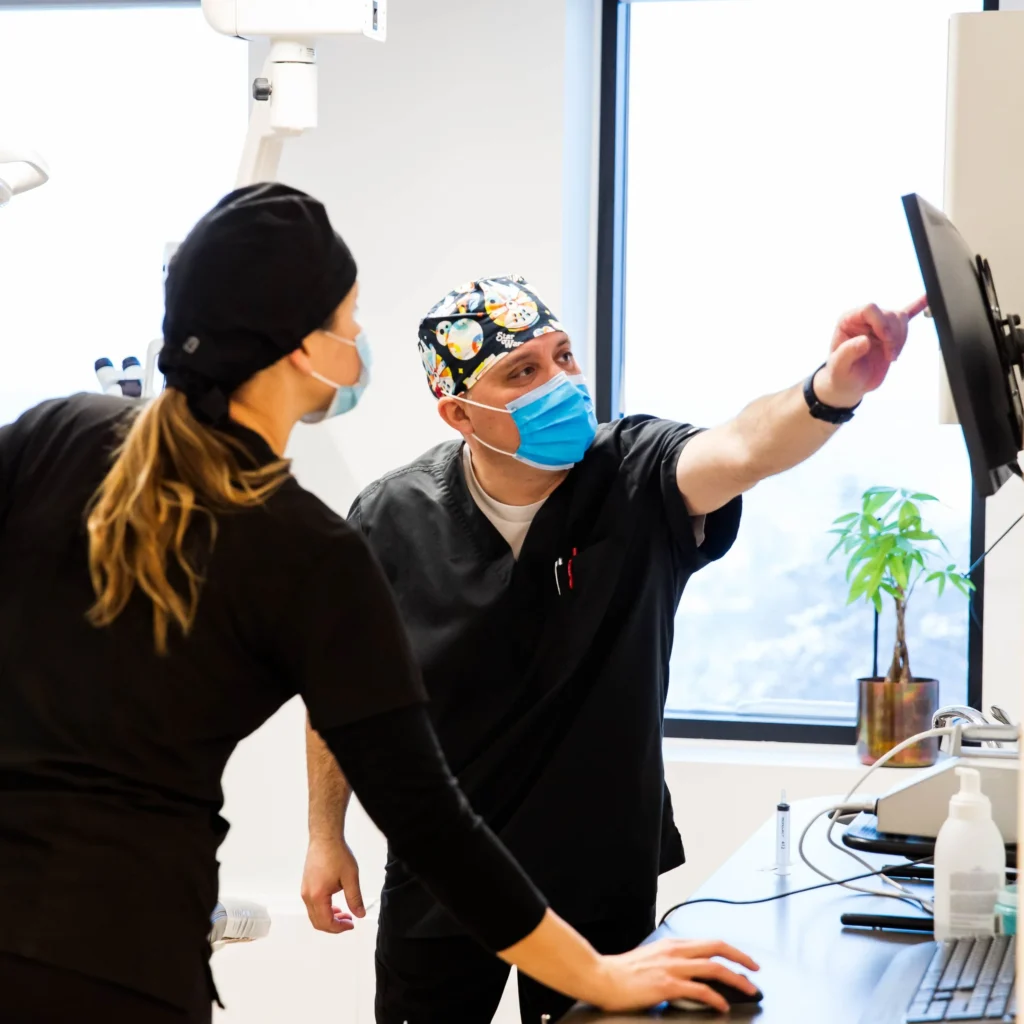Dentist points to screen with assistant